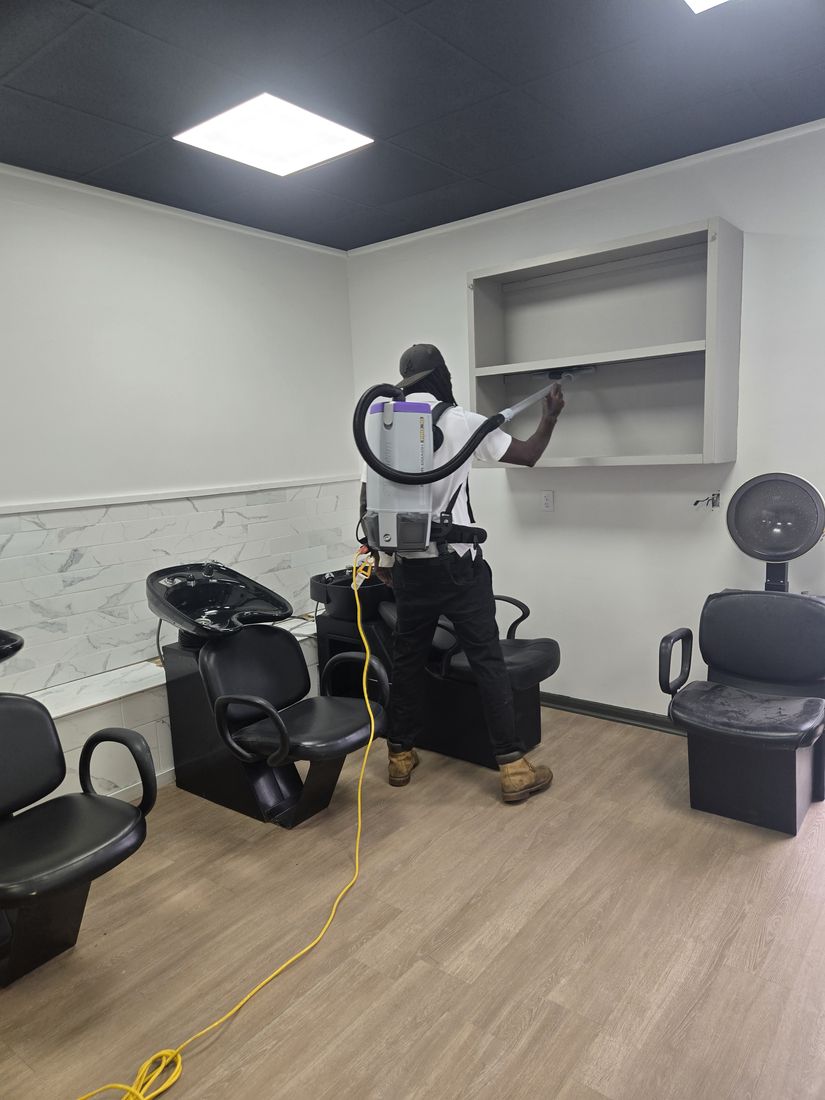 Kidoti Clean crew member vacuuming construction dust from wall shelving in a salon suite, Birmingham AL