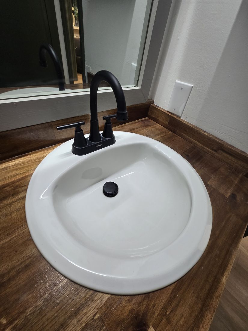 Clean white sink and black faucet on a wood vanity after Kidoti Clean post-construction cleaning, Birmingham AL